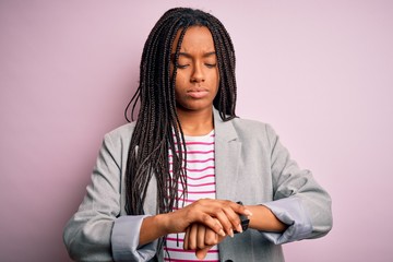 Young african american business woman standing over pink isolated background Checking the time on...