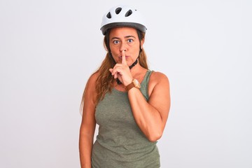 Middle age mature cyclist woman wearing safety helmet over isolated background asking to be quiet with finger on lips. Silence and secret concept.