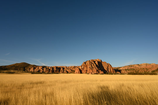 Dry Grassy Field And Red Rocks At Sunset