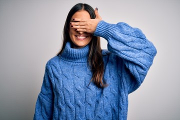 Young beautiful brunette woman wearing casual turtleneck sweater over white background smiling and laughing with hand on face covering eyes for surprise. Blind concept.