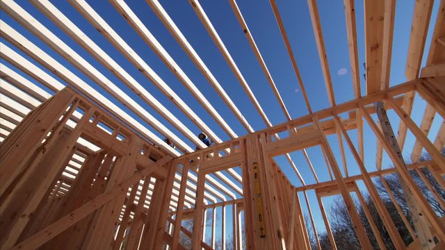 Panoramic timelapse from below of builders working on wooden beams of future second floor. Frame house under construction