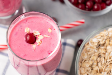 Freshly homemade smoothie of yogurt, oatmeal and cranberries on a gray table. Healthy eating concept