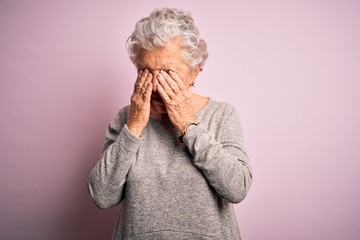 Senior beautiful woman wearing casual t-shirt standing over isolated pink background rubbing eyes...