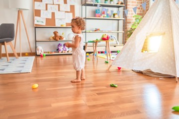 Beautiful caucasian infant playing with toys at colorful playroom. Happy and playful at kindergarten.
