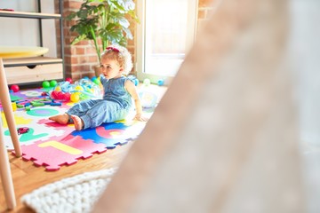 Obraz premium Beautiful caucasian infant playing with toys at colorful playroom. Happy and playful at kindergarten.