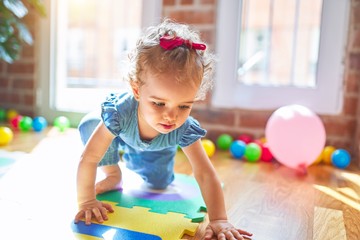 Beautiful caucasian infant playing with toys at colorful playroom. Happy and playful at kindergarten. - obrazy, fototapety, plakaty