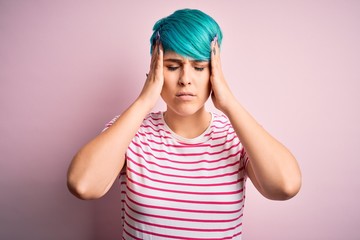 Obraz na płótnie Canvas Young beautiful woman with blue fashion hair wearing casual striped t-shirt suffering from headache desperate and stressed because pain and migraine. Hands on head.
