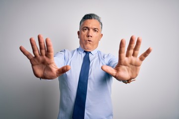 Middle age handsome grey-haired business man wearing elegant shirt and tie doing stop gesture with hands palms, angry and frustration expression