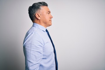 Middle age handsome grey-haired business man wearing elegant shirt and tie looking to side, relax profile pose with natural face and confident smile.