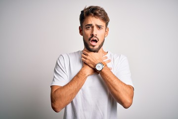 Young handsome man with beard wearing casual t-shirt standing over white background shouting and...