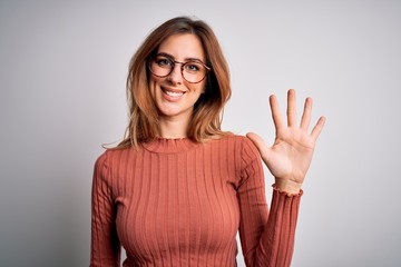 Young beautiful brunette woman wearing casual sweater and glasses over white background showing and pointing up with fingers number five while smiling confident and happy.