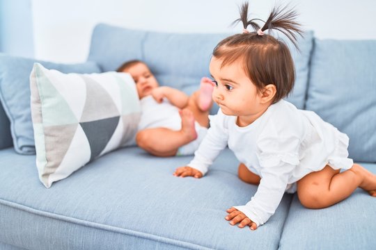 Beautiful infant happy girls playing together at home kindergarten sitting on the sofa