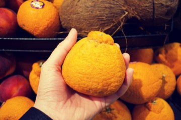 Hand holding blood orange in supermarket