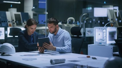 Industry 4.0 Modern Factory Meeting Room: Chief Engineer Holds Digital Tablet Computer, Shows it to Female Specialist, They Have Discussion. Design Electronic Machinery With Futuristic Design