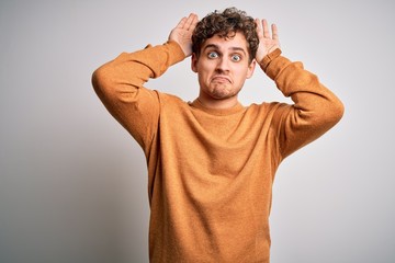 Young blond handsome man with curly hair wearing casual sweater over white background Doing bunny ears gesture with hands palms looking cynical and skeptical. Easter rabbit concept.