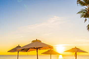 Fototapeta na wymiar Beautiful tropical nature umbrella chair with palm tree around beach sea ocean at sunset or sunrise
