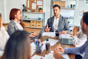 Group of business workers working together. Sitting on desk using laptop reading documents at the office