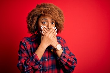 Young beautiful African American afro woman with curly hair wearing casual shirt shocked covering mouth with hands for mistake. Secret concept.