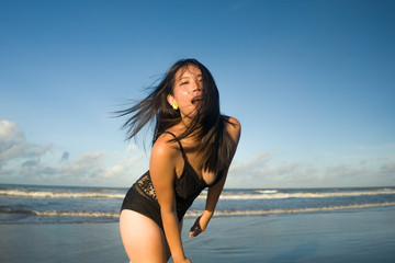 natural lifestyle portrait of young attractive and happy Asian Japanese woman in swimsuit walking on beautiful beach paradise feeling relaxed and cheerful enjoying holidays
