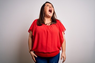 Beautiful brunette plus size woman wearing casual red t-shirt over isolated white background angry and mad screaming frustrated and furious, shouting with anger. Rage and aggressive concept.