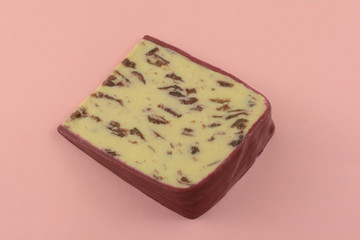 Slice of Wensleydale cranberry cheese with wax edges on pink background 