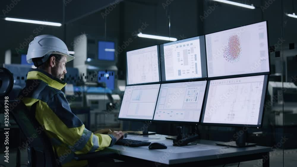 Leinwandbilder Industry 4.0 Modern Factory: Facility Operator Controls Workshop Production Line, Uses Computer with Screens Showing Complex UI of Machine Operation Processes, Controllers, Machinery Blueprints