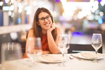 Young beautiful girl smiling happy and confident sitting on chair at restaurant. Relaxing with a smile on face