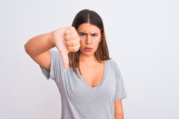 Portrait of beautiful young woman standing over isolated white background looking unhappy and angry showing rejection and negative with thumbs down gesture. Bad expression.