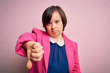 Young down syndrome business woman over pink background looking unhappy and angry showing rejection...