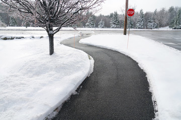Winding pedestrian sidewalk with snow removed after winter snow