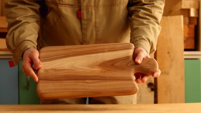 Woodworker showing beautiful wood cutting board from elm wood