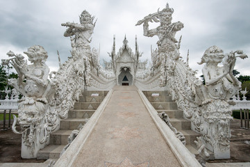 Beautiful architecture of White temple (Wat Rong Khun)  in Chiang Rai province of Thailand in the cloudy day. The Wat Rong Khun was designed by Chalermchai Kositpipat, a famous Thai visual artist.
