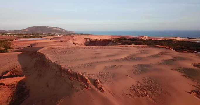 Aerial shot of huge red sand dune near Mui Ne, Vietnam with sea visible in the far background