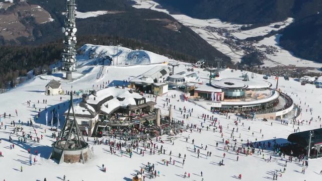 Aerial view of the Kronplatz mountain, the Dolomites, Italy. Concordia bell is ringing, hundreds of skiers move on the plateau. It is sunny, the sky is clear, the valley below is covered with snow.