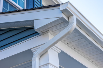Colonial white gutter guard system, fascia, drip edge, soffit providing ventilation to the attic, with pacific blue vinyl horizontal siding at a luxury American single family home neighborhood USA - obrazy, fototapety, plakaty