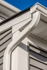 Colonial white gutter guard system,  soffit providing ventilation to the attic, with gray vinyl horizontal siding at a luxury American single family home neighborhood USA © tamas