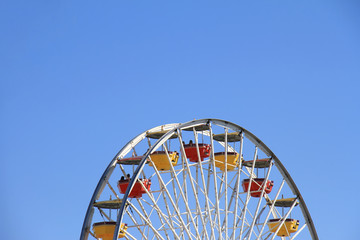 Ferris wheels over clear blue sky background at amusement park, Colorful pleasure wheels swept around against horizon, Childhood happy memory and fun time, Minimal style.