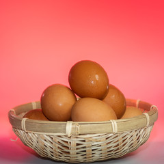 Fresh eggs with water condensation in a rattan basket. Isolated on Red background. Shallow depth of field.
