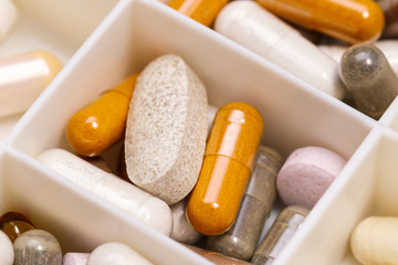 plastic medicine organizer with pills and capsules, medicines for health, pharmaceutical health care and sciences concept, shallow depth of field