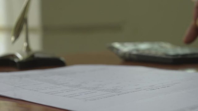 Human hand calculating business finance investment report using calculator - adding machine tape. Business finance and industry, accountancy concepts. Close up.