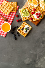 Obraz na płótnie Canvas Breakfast with freashly baked belgian waffles on grey background top-down frame copy space