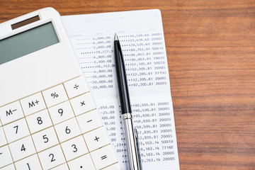 Bank balance sheet with pen and calculator on wooden table using as income, cost and expense, investment or personal finance concept