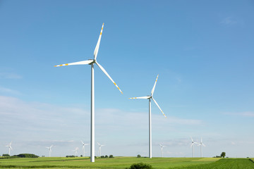 wind turbines in green field, countryside area with blue sky
