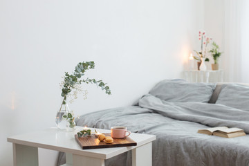 interior of bedroom with bouquet, candles and cup of tea