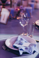 the festive table at the wedding party is decorated with flower arrangements, on the table are plates with napkins, glasses, candles, cutlery