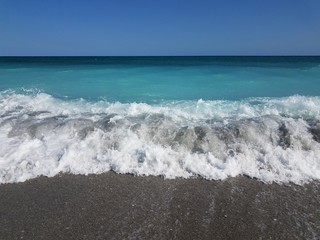 Fototapeta na wymiar white waves crashing on sand with ocean