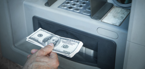 Hand holding dollars withdrawn from ATM.