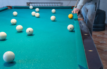 Green billiard table with white balls. Young man playing billiards