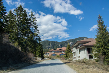 Fototapeta na wymiar March 25, 2019 - Smolyan, Bulgaria - Road in the mountains with hotels on the side, beautiful blue sky, forest, trees