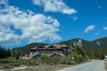 March 25, 2019 - Smolyan, Bulgaria - Road in the mountains with hotels on the side, beautiful blue sky, forest, trees